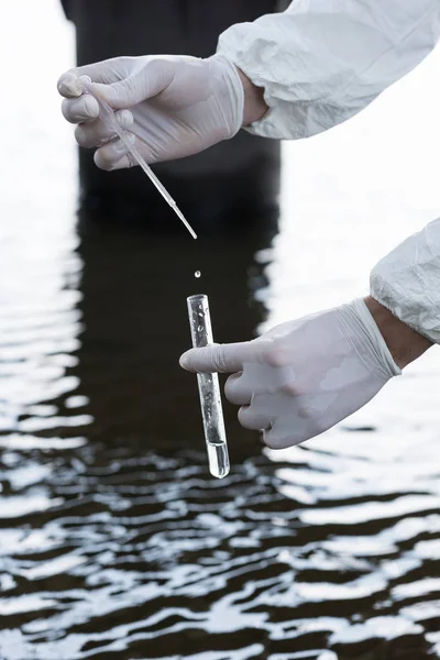 Visão recortada do inspetor de água em luvas de látex retirando amostra de água no rio — Fotografia de Stock
