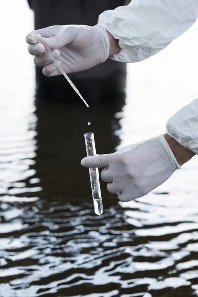 Cropped view of water inspector in latex gloves taking water sample at river — Stock Photo