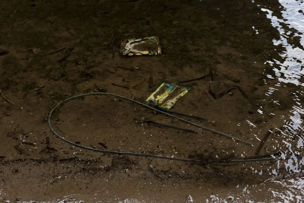 Basura plástica sobre fondo arenoso texturizado en el río - foto de stock