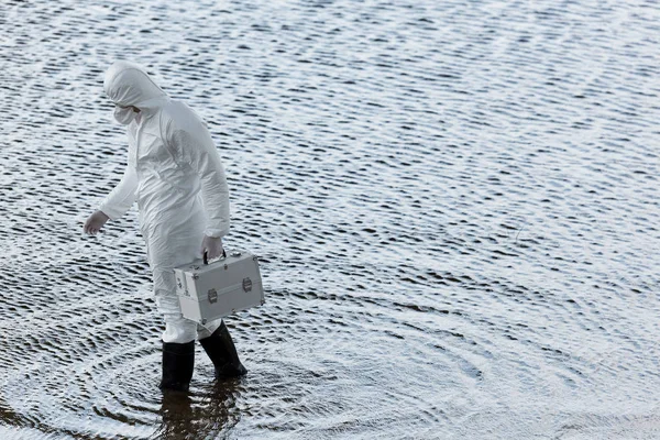 Full length view of water inspector in protective costume holding inspection kit at river — Stock Photo