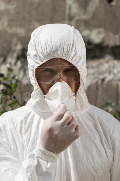 Frontansicht des Ökologen in Schutzkleidung und Schutzbrille beim Ausziehen der Atemschutzmaske — Stockfoto