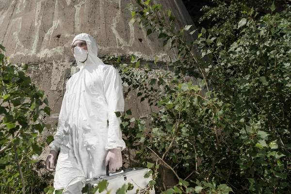 Vue à angle bas de l'écologiste avec kit d'inspection debout près des plantes — Photo de stock