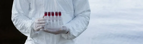 Panoramic shot of water inspector in latex gloves holding test tubes — Stock Photo