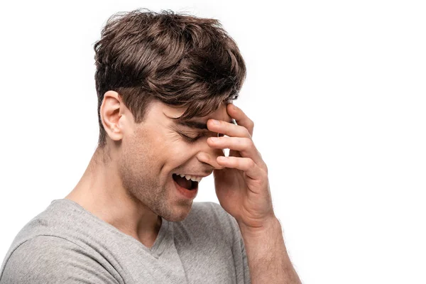 Positive young man smiling with closed eyes and holding hand near face isolated on white — Stock Photo