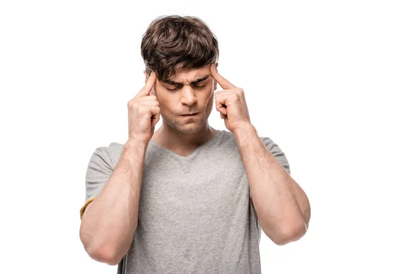 Tired young man touching head with fingers while standing with closed eyes isolated on white — Stock Photo