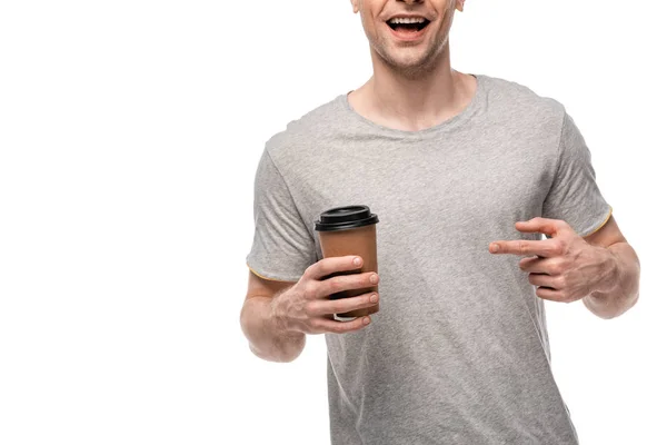 Vue recadrée de l'homme souriant pointant avec doigt et tasse en papier isolé sur blanc — Photo de stock