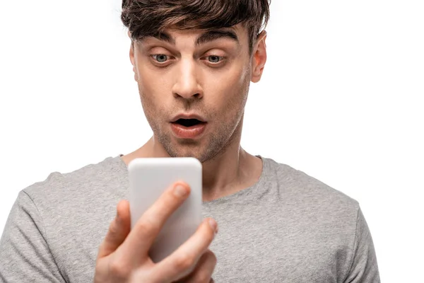Bonito, jovem surpreso olhando para smartphone isolado no branco — Fotografia de Stock
