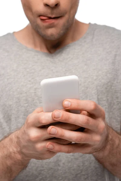 Vue partielle de l'homme lécher les lèvres tout en utilisant smartphone isolé sur blanc — Photo de stock