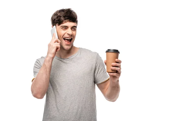 Jovem alegre falando no smartphone e segurando café para ir isolado no branco — Fotografia de Stock