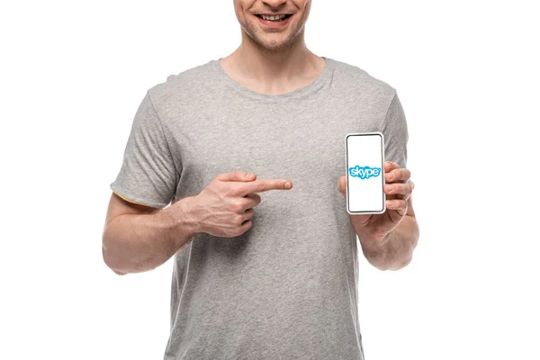 KYIV, UKRAINE - MAY 16, 2019: cropped view of smiling man pointing at smartphone with skype app, isolated on white — Stock Photo