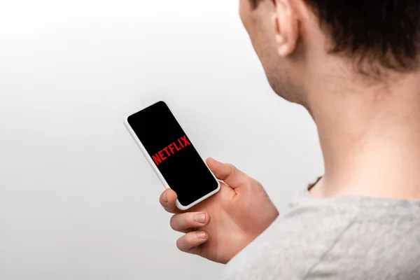 KYIV, UKRAINE - 16 MAI 2019 : vue recadrée de l'homme à l'aide d'un smartphone avec application netflix, isolé sur gris — Photo de stock