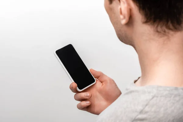 Обрізаний вид людини, що тримає смартфон з порожнім екраном ізольовано на сірому — стокове фото