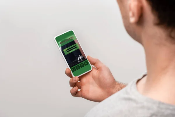 Cropped view of man using smartphone with booking app, isolated on grey — Stock Photo