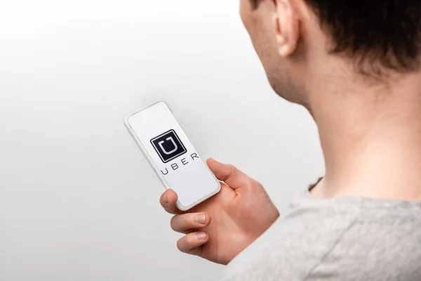 KYIV, UCRANIA - 16 de mayo de 2019: vista recortada del hombre usando un teléfono inteligente con aplicación uber, aislado en gris - foto de stock