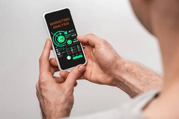 Vue recadrée de l'homme à l'aide d'un smartphone avec application d'analyse marketing, isolé sur gris — Photo de stock