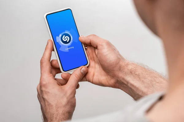 KYIV, UKRAINE - MAY 16, 2019: cropped view of man using smartphone with shazam app, isolated on grey — Stock Photo