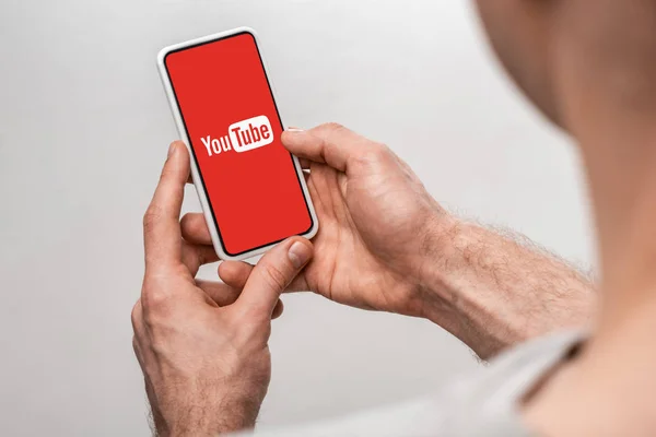 KYIV, UKRAINE - MAY 16, 2019: cropped view of man using smartphone with youtube app, isolated on grey — Stock Photo