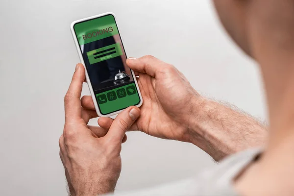 Cropped view of man using smartphone with booking app, isolated on grey — Stock Photo