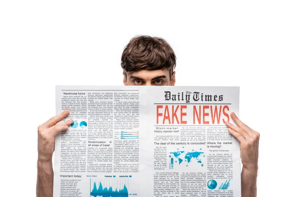 Young man looking at camera while holding newspaper with gake news isolated on white — Stock Photo