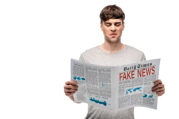 Незадоволений молодий чоловік читає газету з фальшивими новинами ізольовані на білому — стокове фото