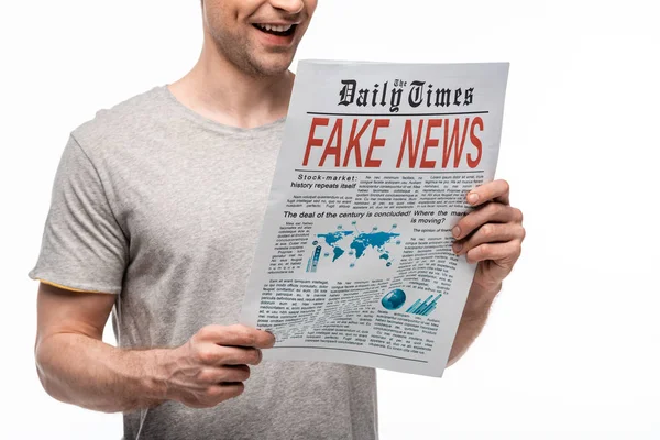 Partial view of young smiling man reading newspaper with fake news isolated on white — Stock Photo
