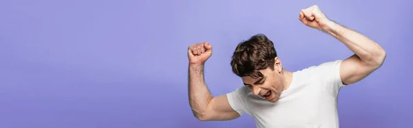 Tiro panorâmico de jovem feliz mostrando gesto vencedor isolado em azul — Fotografia de Stock