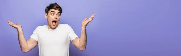 Panoramic shot of handsome man showing shrug gesture on blue background — Stock Photo