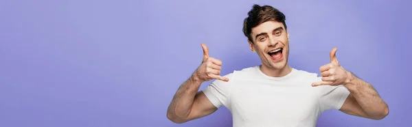 Panoramaaufnahme eines gut gelaunten Mannes, der auf blauem Hintergrund Gesten zeigt und in die Kamera lächelt — Stockfoto