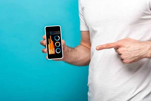 Cropped view of man pointing at smartphone with infographic, isolated on blue — Stock Photo