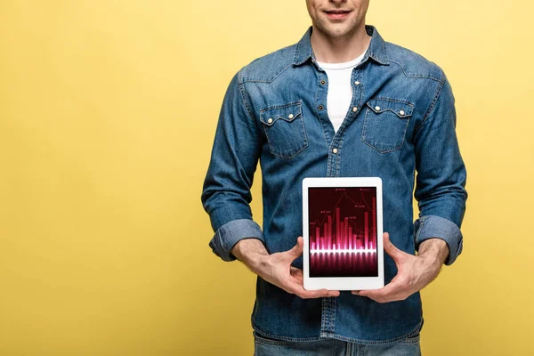 Cropped view of man in denim clothes holding digital tablet with graph, isolated on yellow — Stock Photo