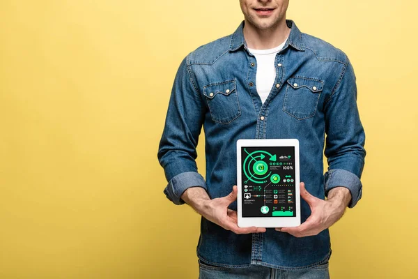 Cropped view of man in denim clothes holding digital tablet with infographic, isolated on yellow — Stock Photo