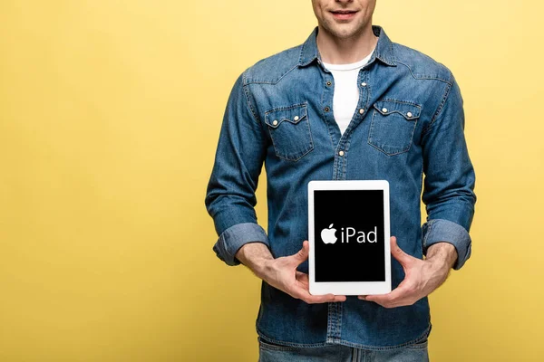 KYIV, UKRAINE - MAY 16, 2019: cropped view of man in jeans clothes showing digital tablet with iPad app, isolated on yellow — Stock Photo