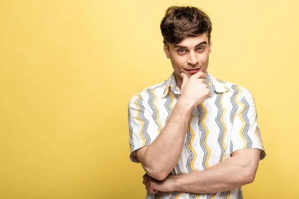 Joven positivo mirando a la cámara mientras sostiene la mano cerca de la cara sobre fondo amarillo - foto de stock