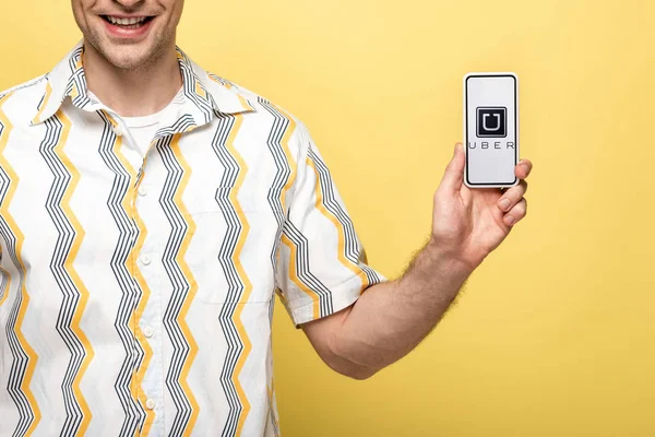 KYIV, UKRAINE - MAY 16, 2019: cropped view of smiling man showing smartphone with uber app, isolated on yellow — Stock Photo