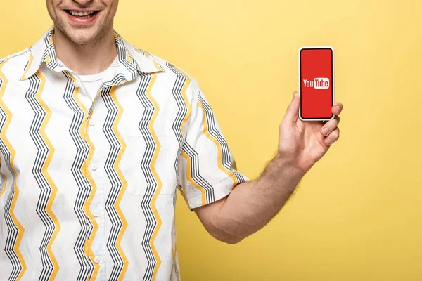 Kyiv, ukraine - 16. Mai 2019: abgeschnittene Ansicht eines lächelnden Mannes, der ein Smartphone mit Youtube-App zeigt, isoliert auf gelb — Stockfoto