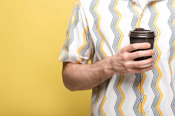 Cropped view of man in colorful shirt holding disposable cup on yellow background — Stock Photo