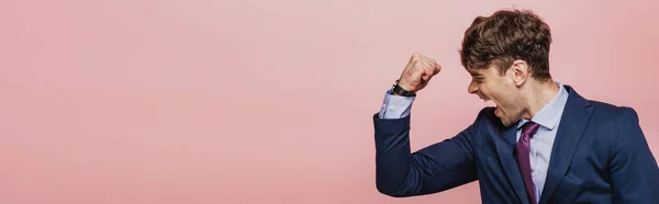 Tiro panorâmico de empresário irritado mostrando punho isolado em rosa — Fotografia de Stock