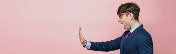 Panoramic shot of angry businessman showing stop gesture isolated on pink — Stock Photo