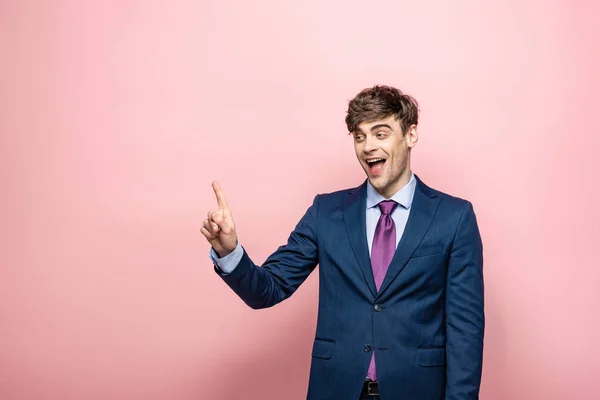 Cheerful businessman looking away and showing idea gesture on pink background — Stock Photo