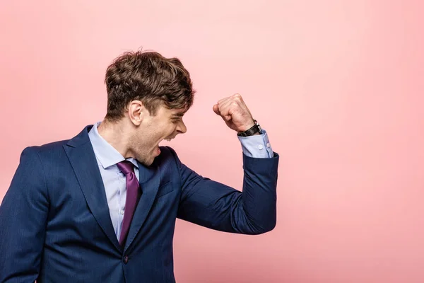 Angry businessman showing fist and screaming on pink background — Stock Photo