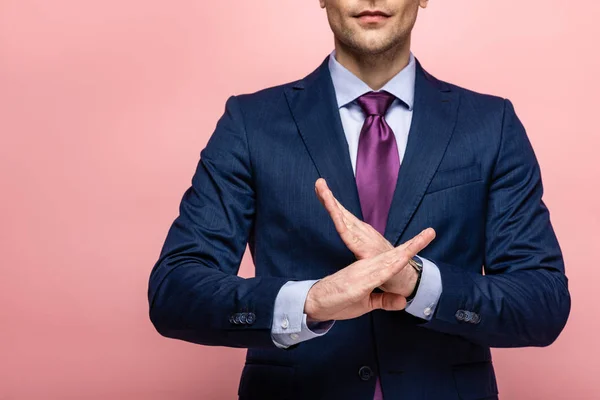 Cropped view of businessman in formal wear showing reject gesture on pink background — Stock Photo