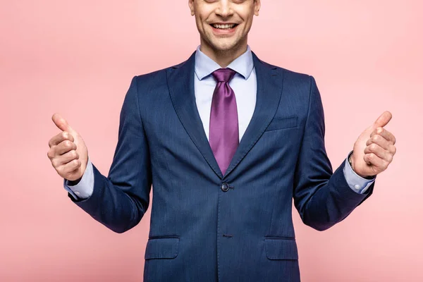 Cropped view of smiling businessman showing thumbs up on pink background — Stock Photo