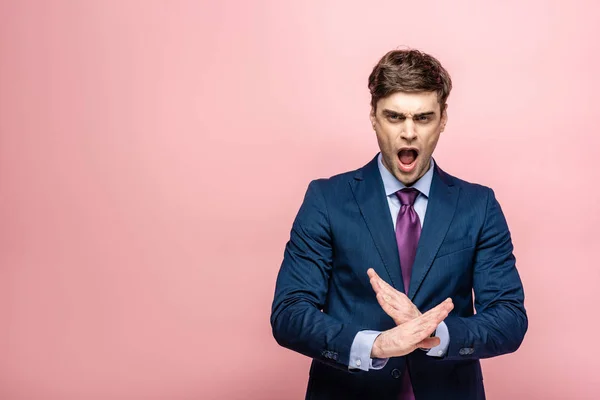 Irritated businessman quarreling and showing stop gesture on pink background — Stock Photo
