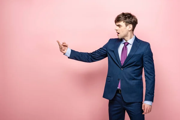 Wütender Geschäftsmann zeigt Mittelfinger, während er auf rosa Hintergrund wegschaut — Stockfoto