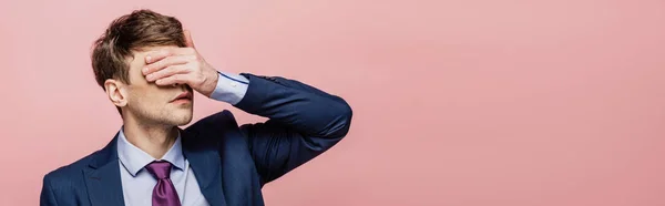 Panoramic shot of businessman covering eyes with hand  isolated on pink — Stock Photo