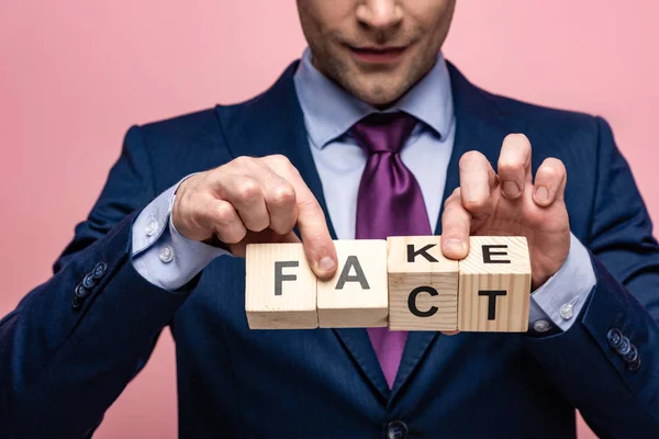 Vista ritagliata di uomo d'affari che mostra cubi di legno con falso lettering fatto isolato su rosa — Foto stock