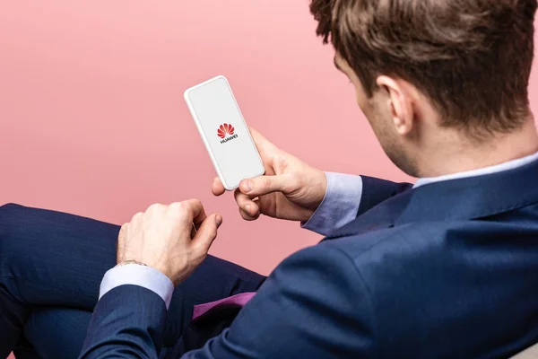 KYIV, UCRAINA - 16 MAGGIO 2019: vista ritagliata dell'uomo d'affari con smartphone con app huawei, isolato su rosa — Foto stock