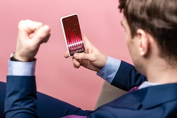 Cropped view of successful businessman using smartphone with trading courses app, isolated on pink — Stock Photo