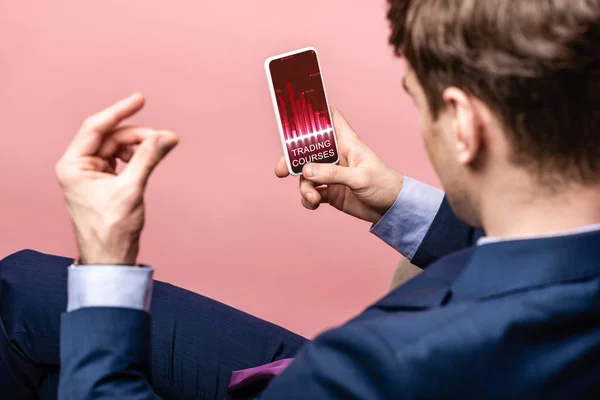 Cropped view of businessman using smartphone with trading courses app, isolated on pink — Stock Photo
