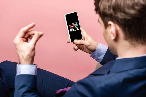 Київ, Україна-16 травня 2019: обрізаний вид бізнесмена використовуючи смартфон з додатком Deezer, ізольований на рожевому — стокове фото
